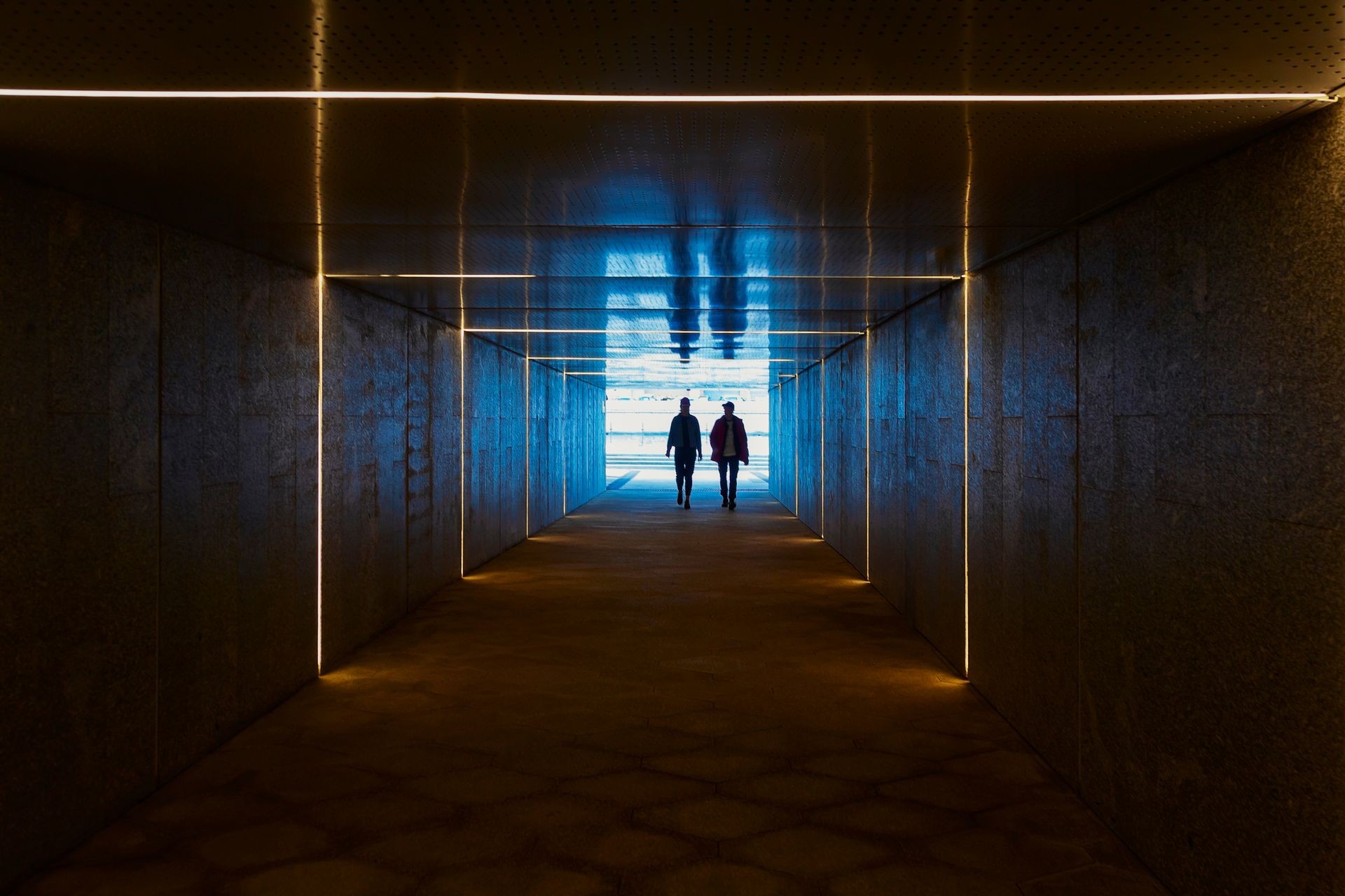 Two men are going from the light insight the dark surrealistic tunnel with concentric light stripes, Moscow, Russia